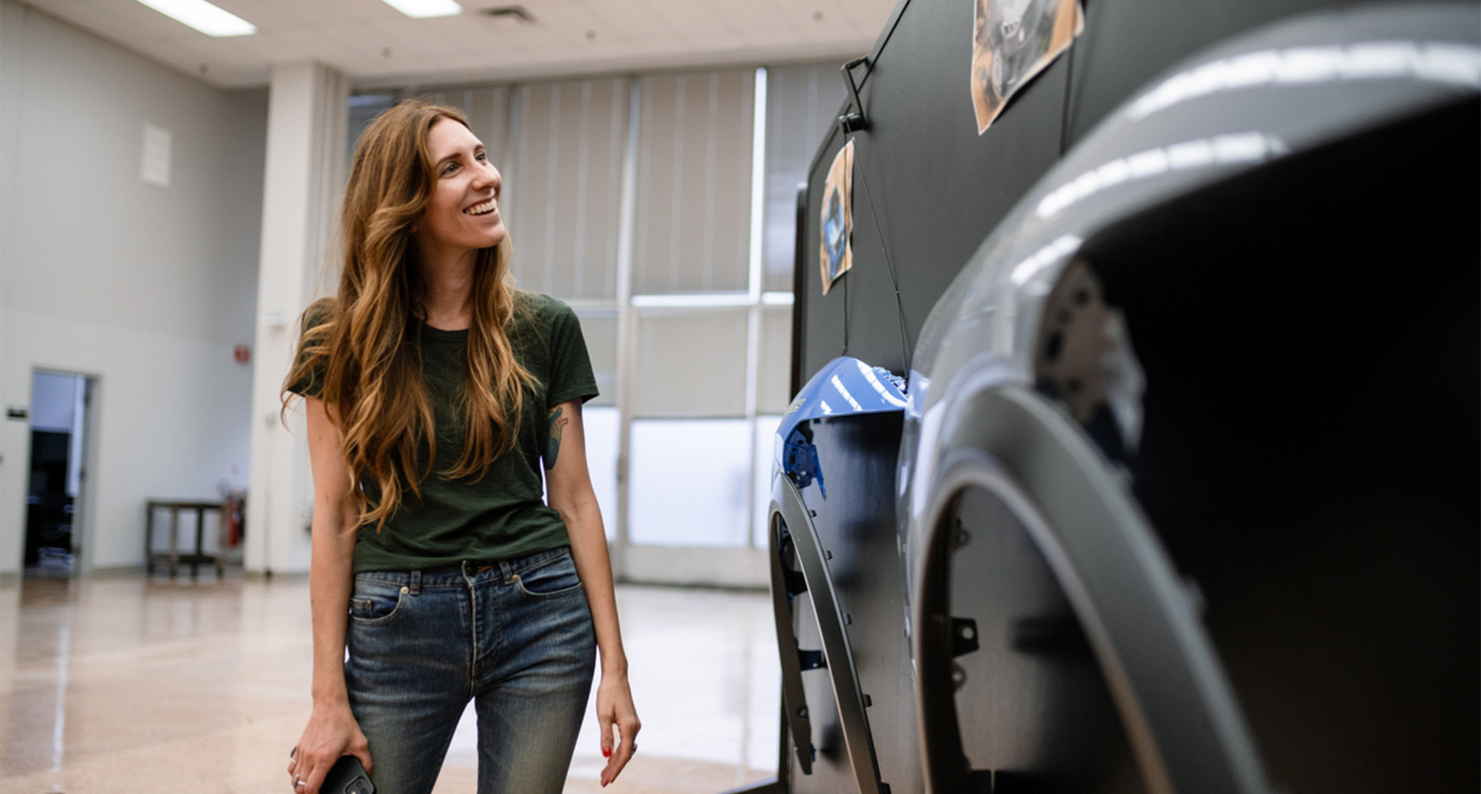 Ford Color and Materials Designer Angela Bell smiles while looking at a wall with automotive design elements on it.