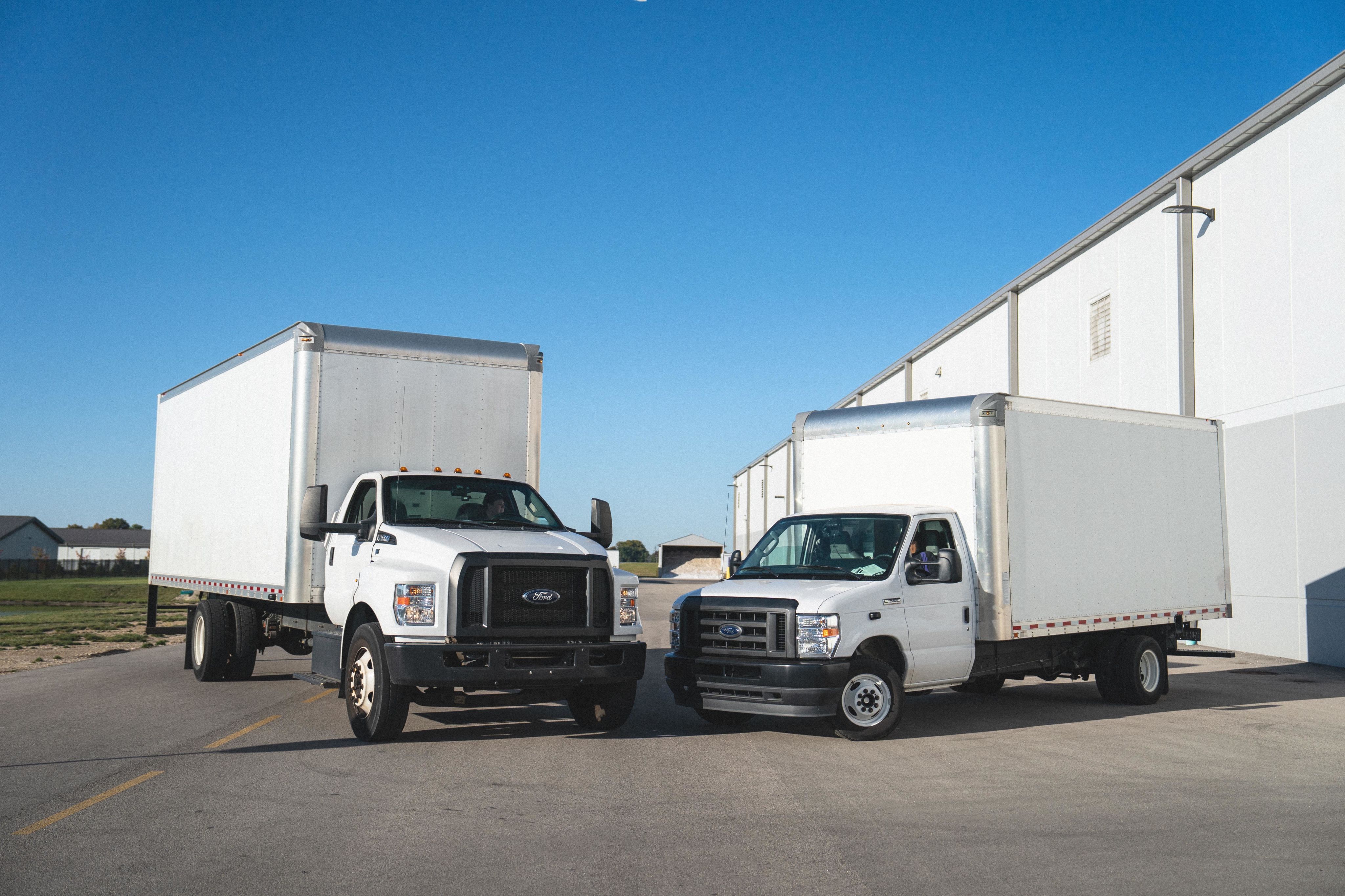 Two Ford chassis box trucks parked