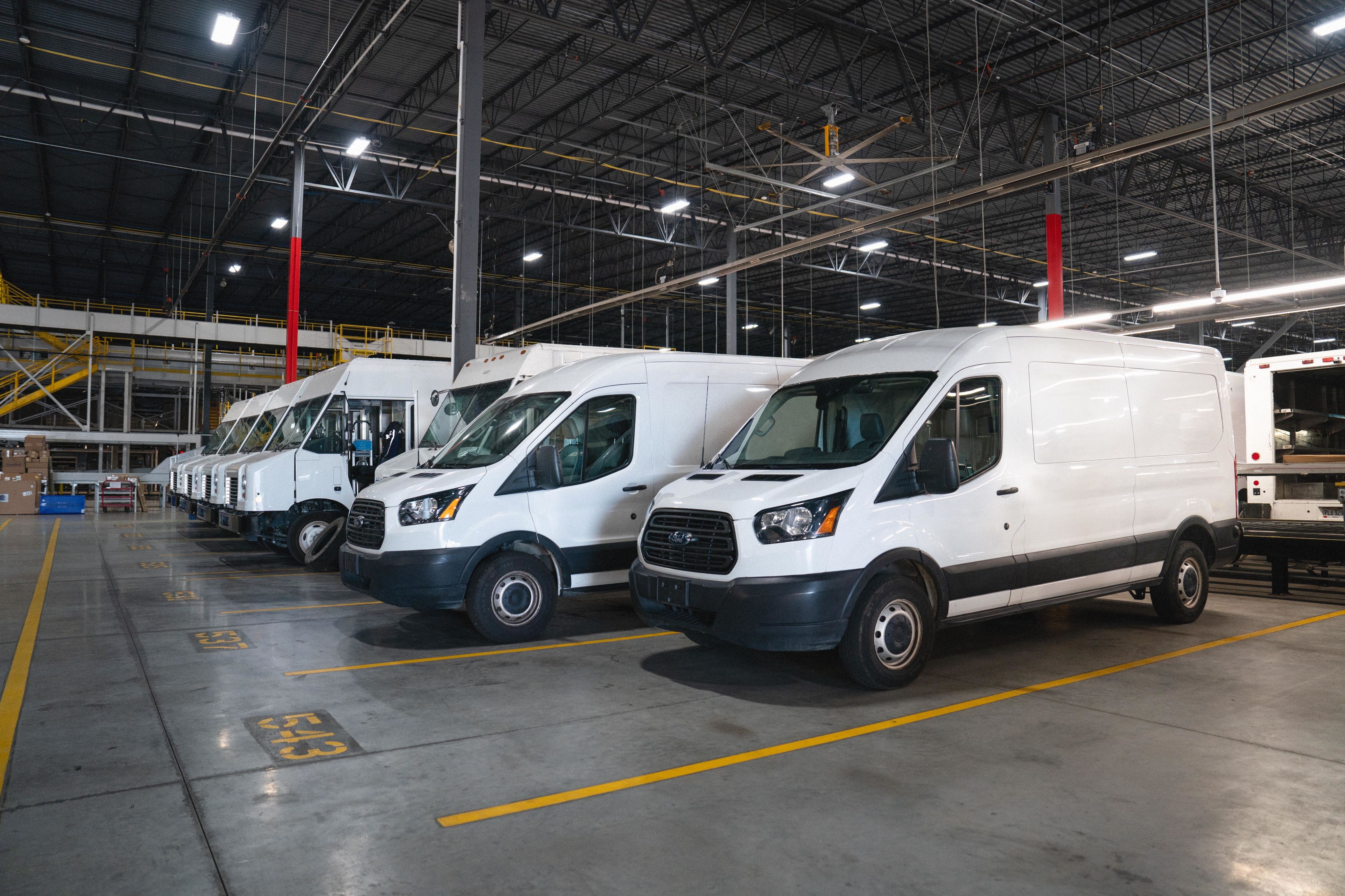 Delivery trucks and vans lined up in a warehouse