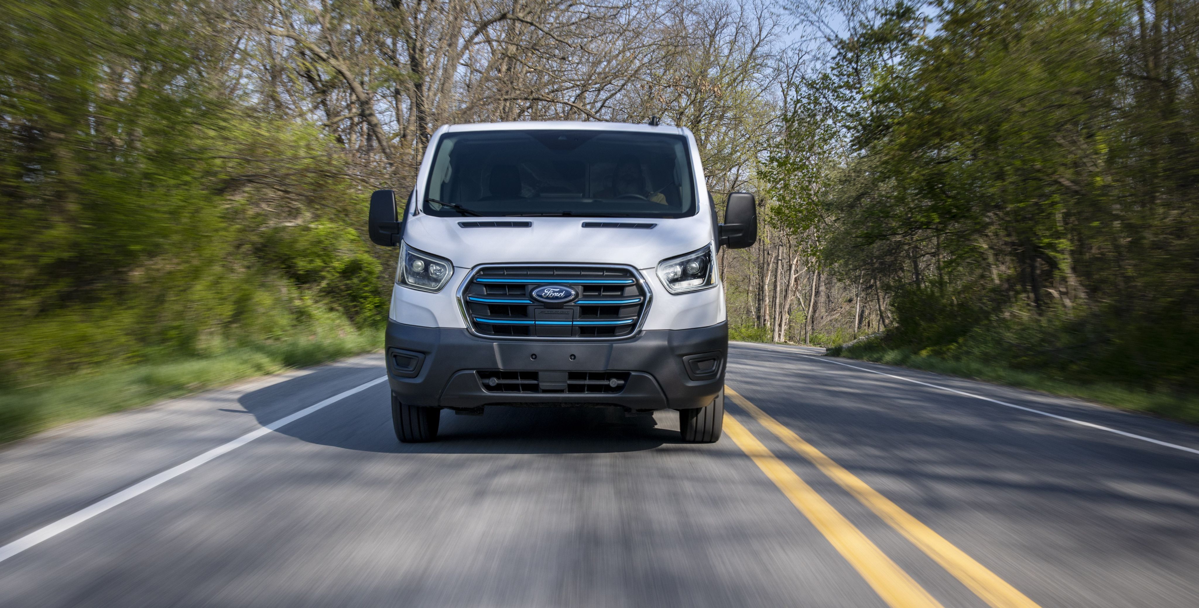 A Ford E-Transit™ van driving down a rural roadway
