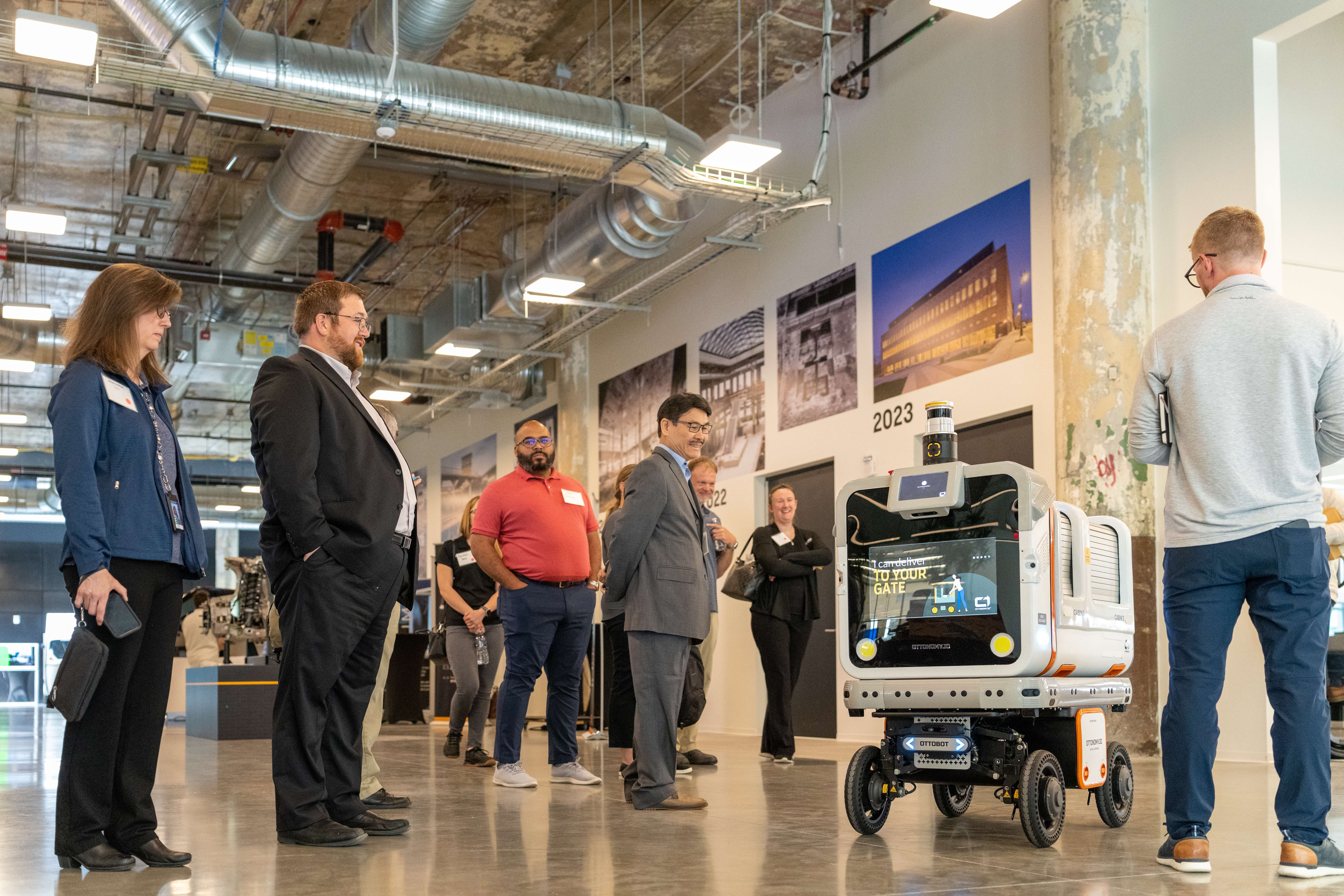 A group of people gather around a piece of technology at an innovation hub