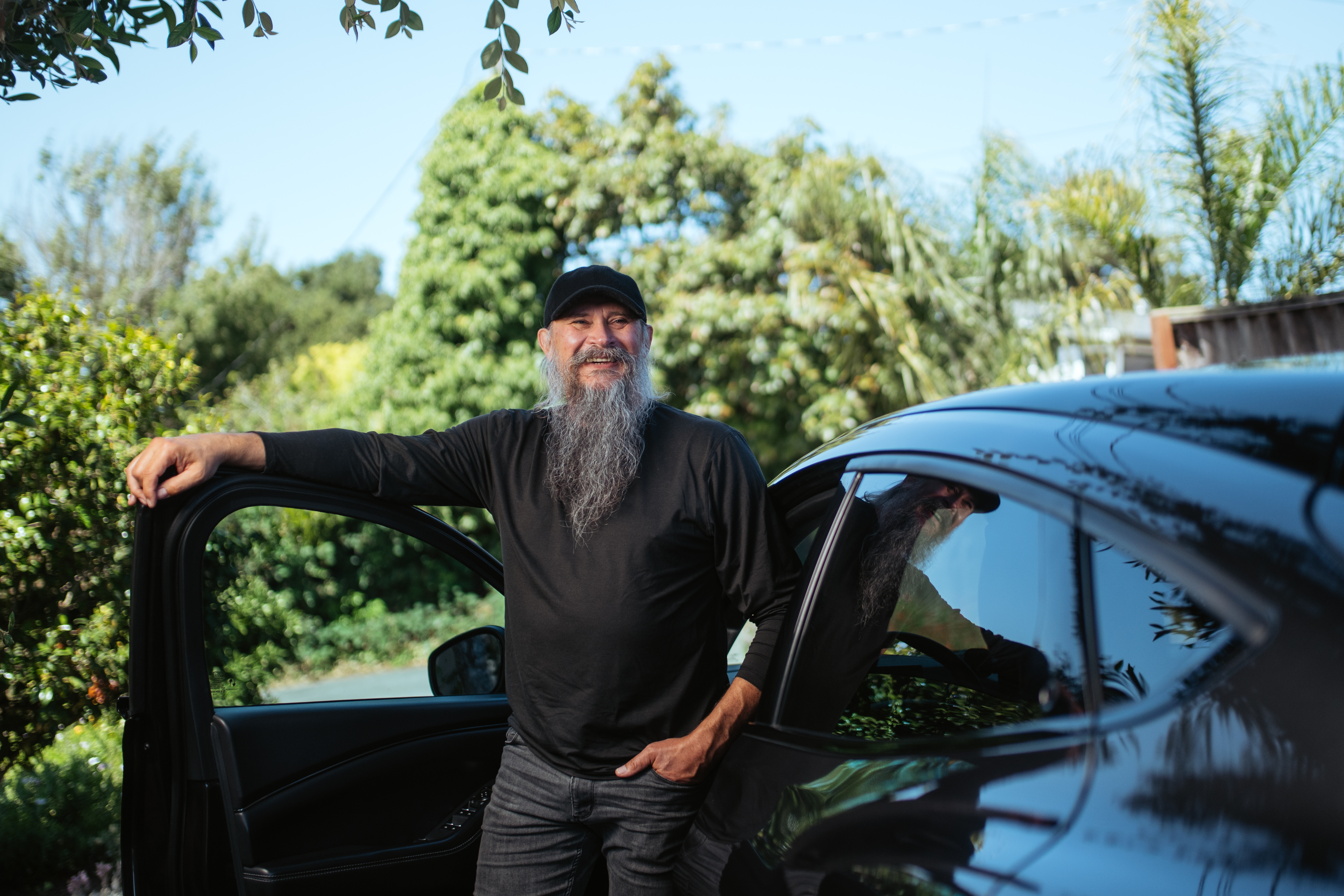 A man poses with his arm on the open car door of his 2022 Mustang Mach-E Premium