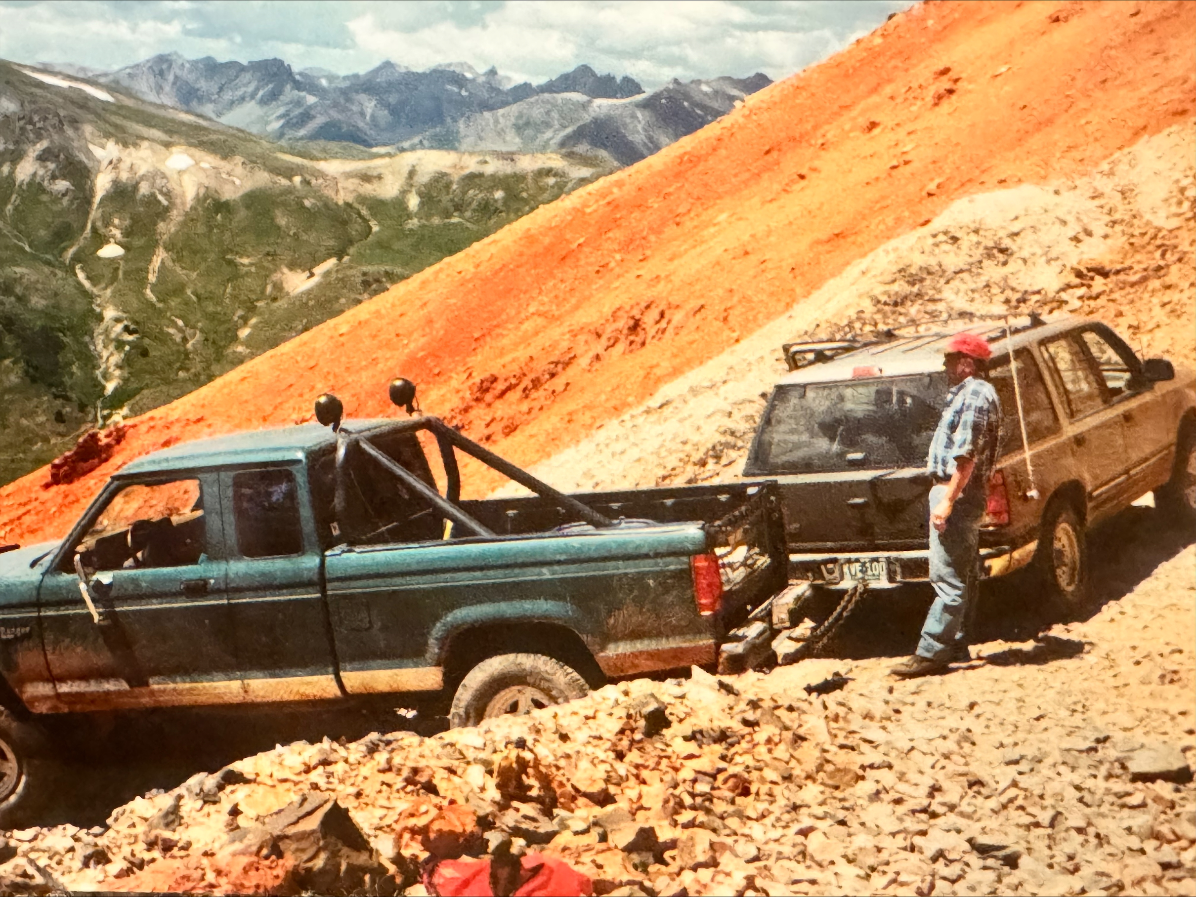 Two off-road vehicles on a rocky hillside in a vintage photograph.