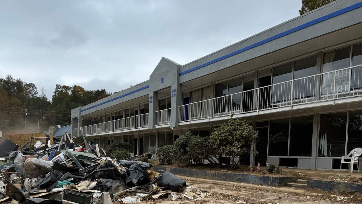 A pile of debris sits in front of a damaged building in the aftermath of a hurricane.