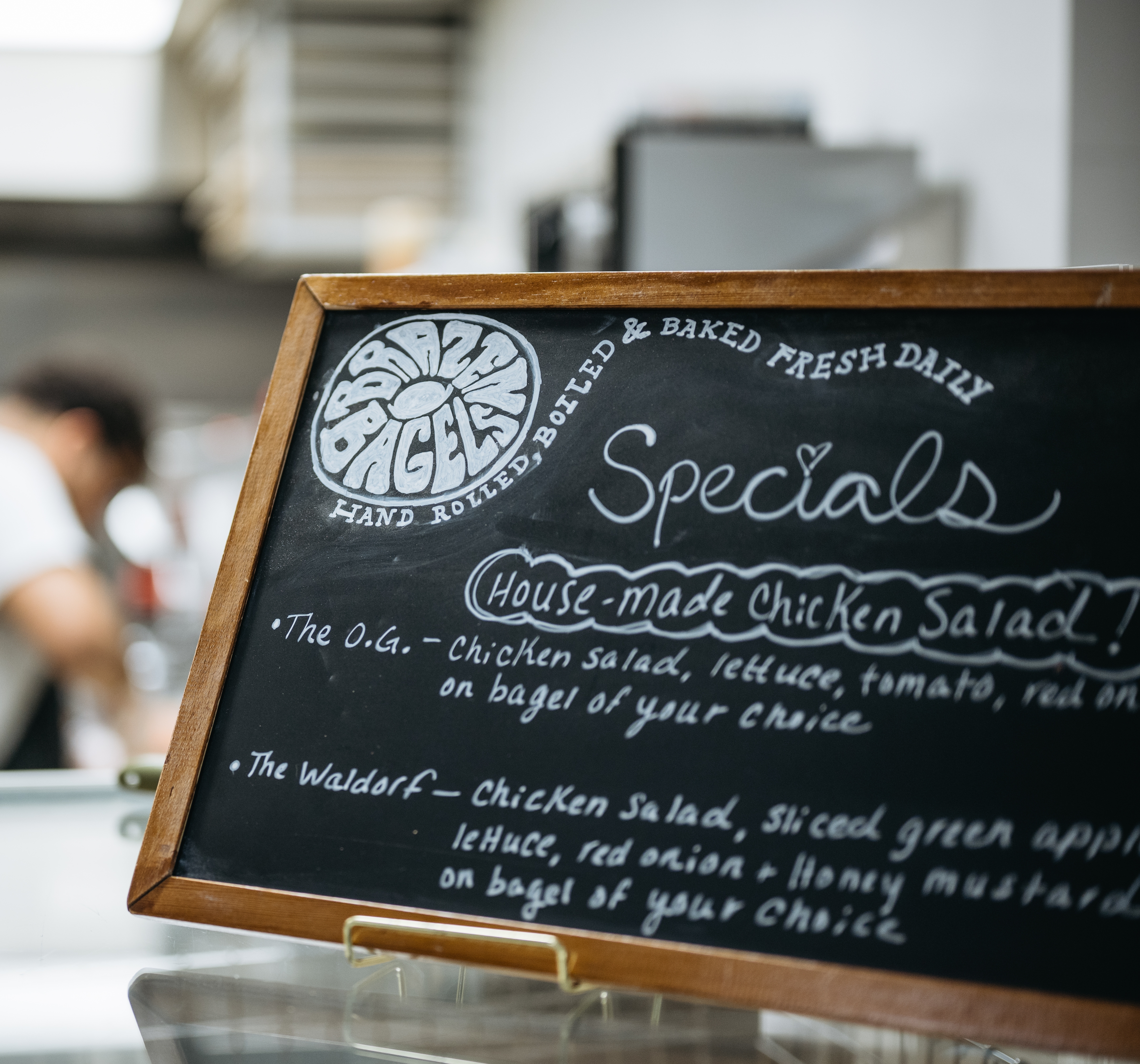 A menu is displayed on the countertop at Brazen Bagels.