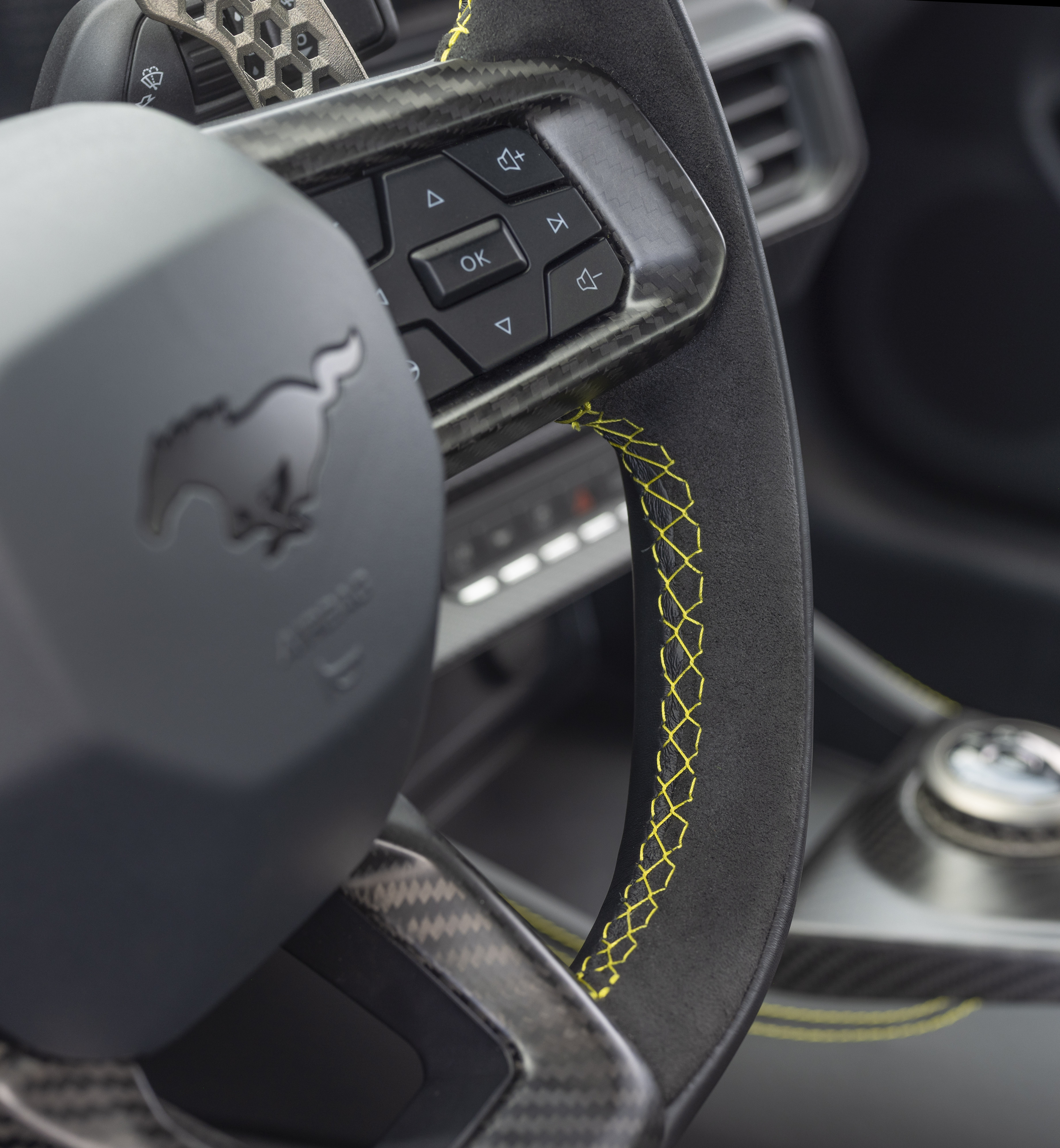 New Mustang Liquid Carbon interior shows lime green stitching on black and grey steering wheel.