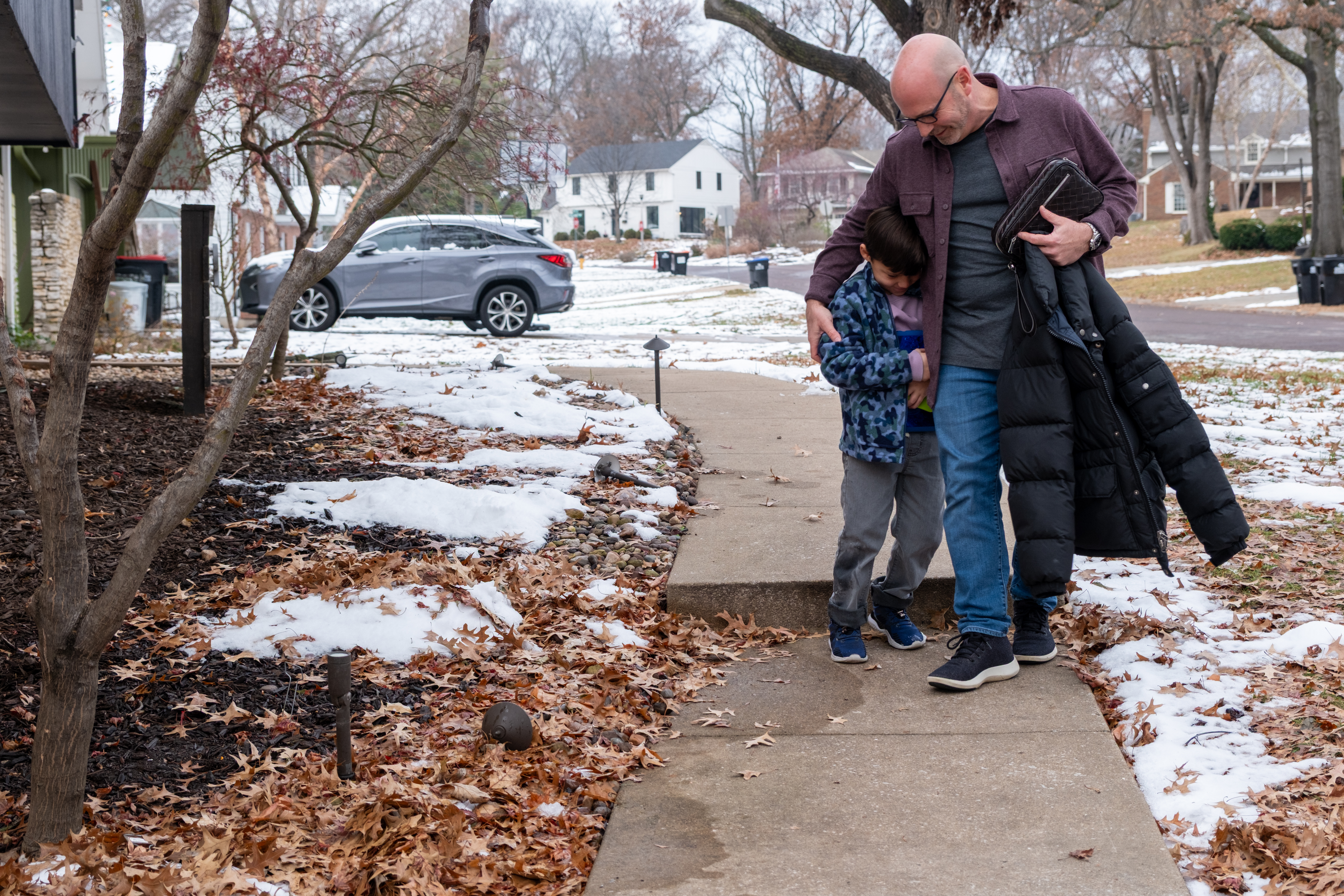 Todd and Oliver walk along the sidewalk, embracing.