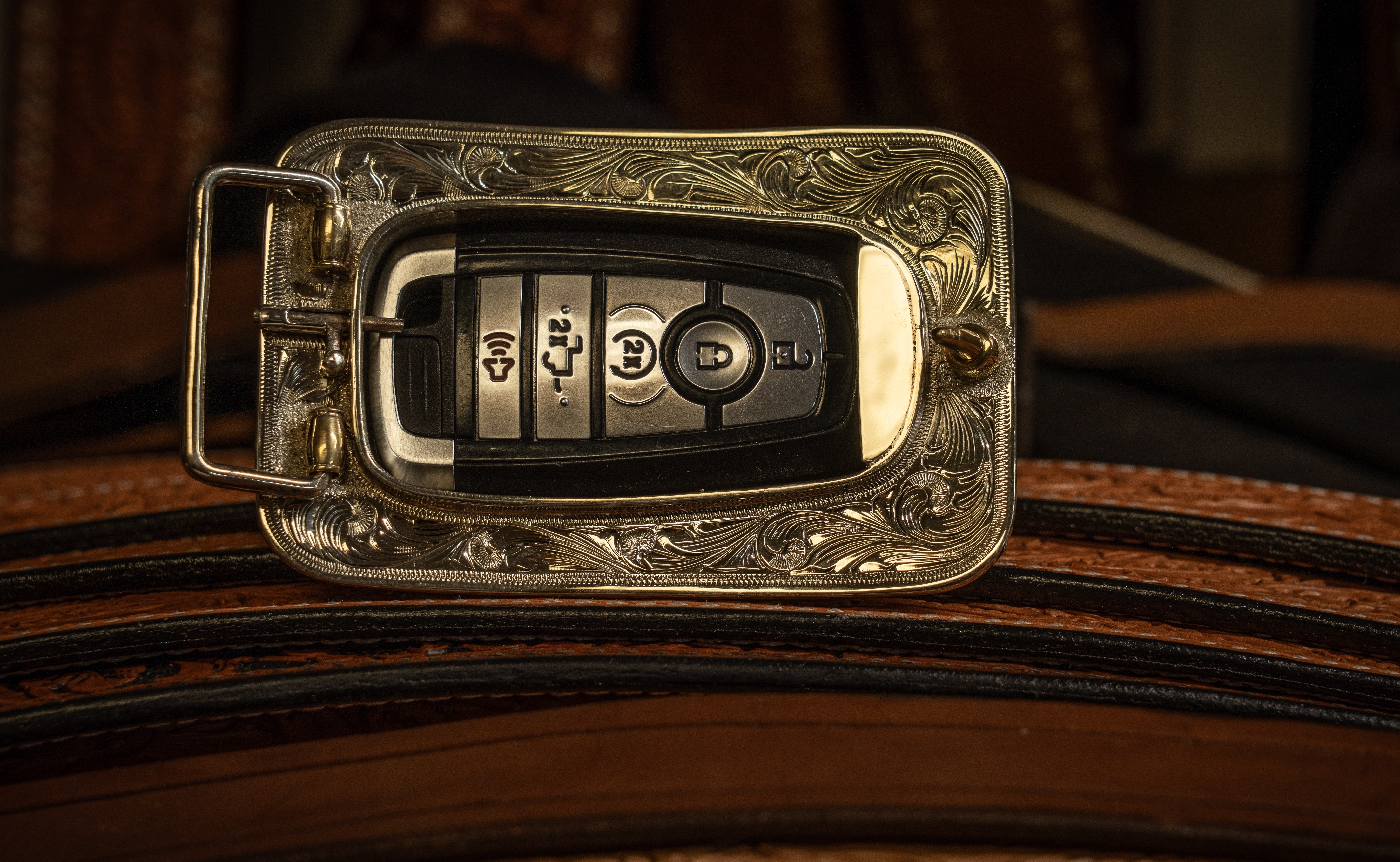 The back of a gold belt buckle is shown holding a key fob.